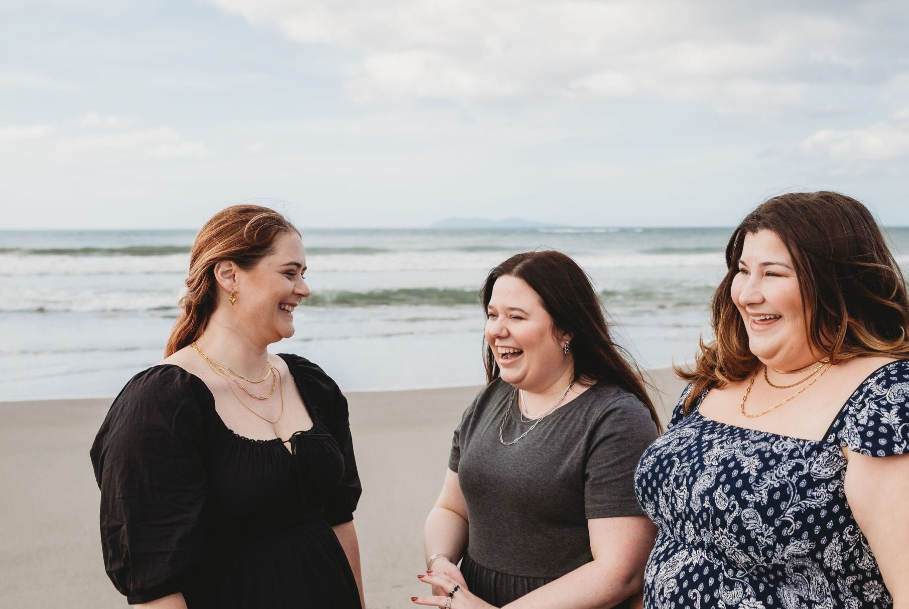 3 friends on the beach in New Zealand laughing and feeling great.