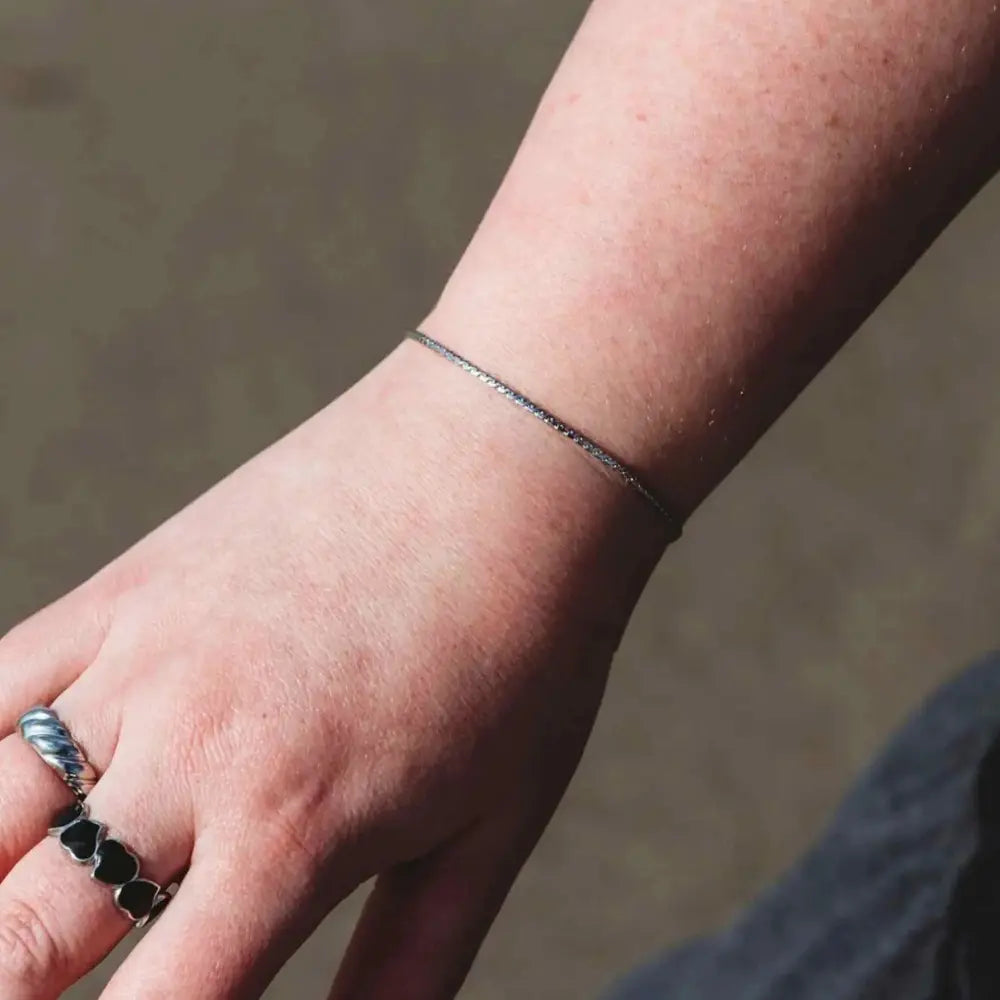 Woman wearing the Delicate Twist silver bracelet with subtle twisted chain detail in stainless steel