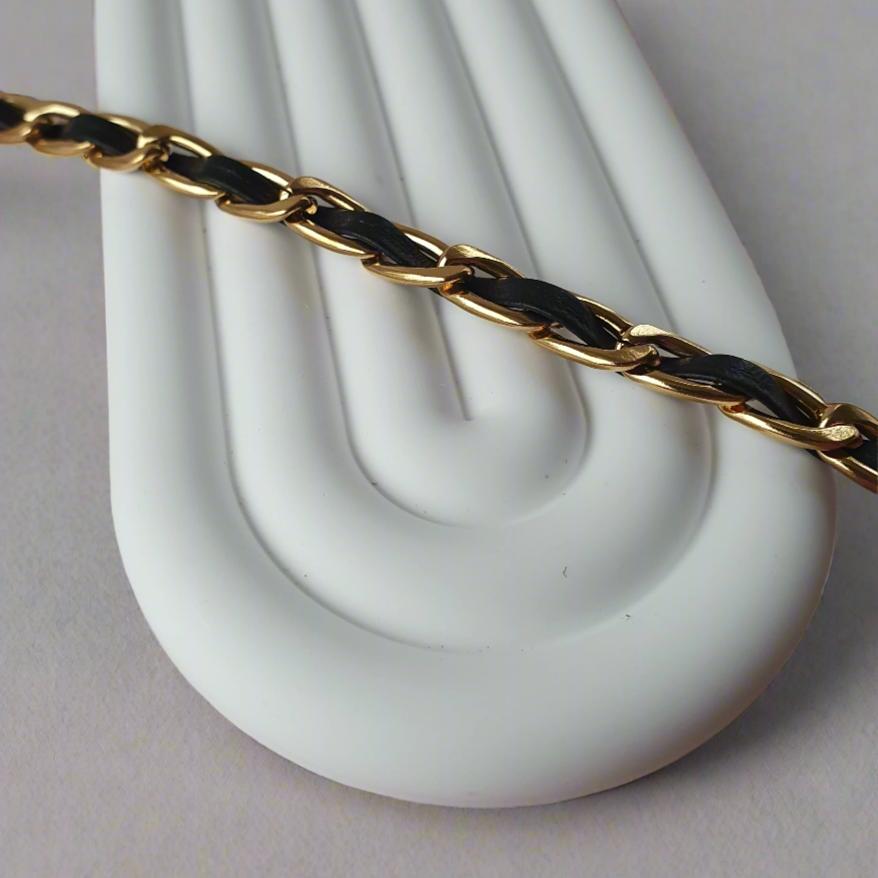 Leather Twist Bracelet featuring a faux leather strip woven through an 18K gold-plated chain, offering a unique blend of edgy style and elegance. Available in a 15cm+5cm length, waterproof, hypoallergenic, and tarnish-resistant.