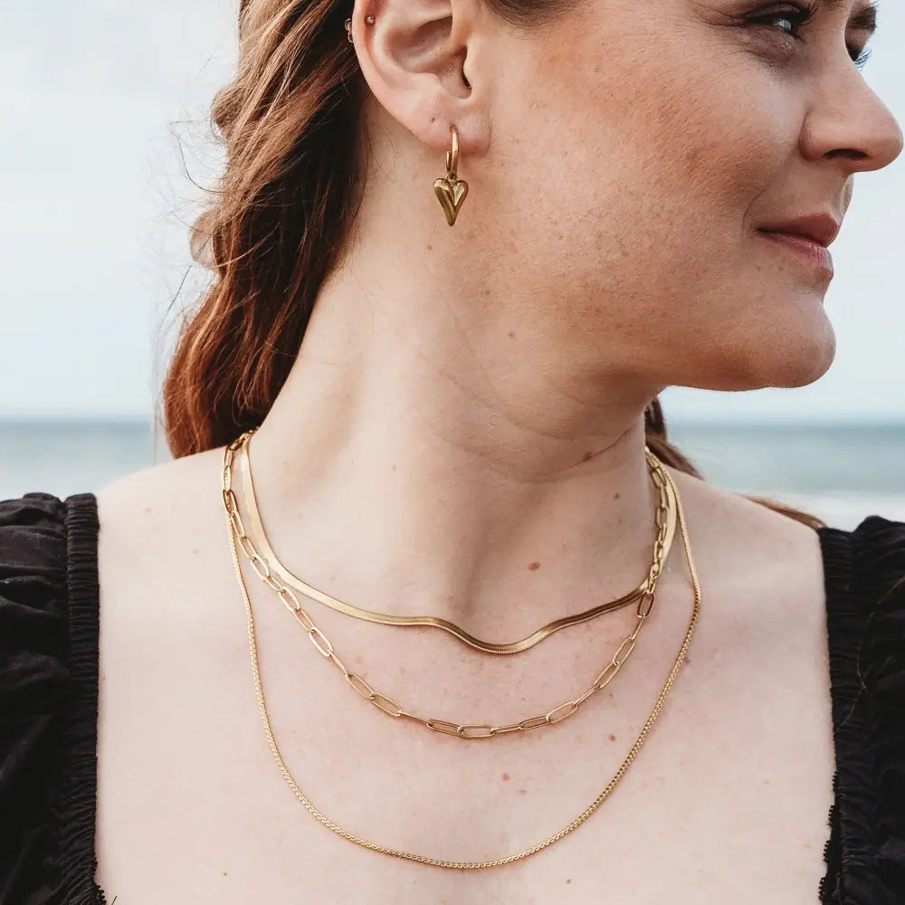 Model showcasing a stacked look with three gold-plated necklaces: Snake Chain, Paperclip Chain, and Delicate Twist Chain. Elegant and versatile, perfect for layering.