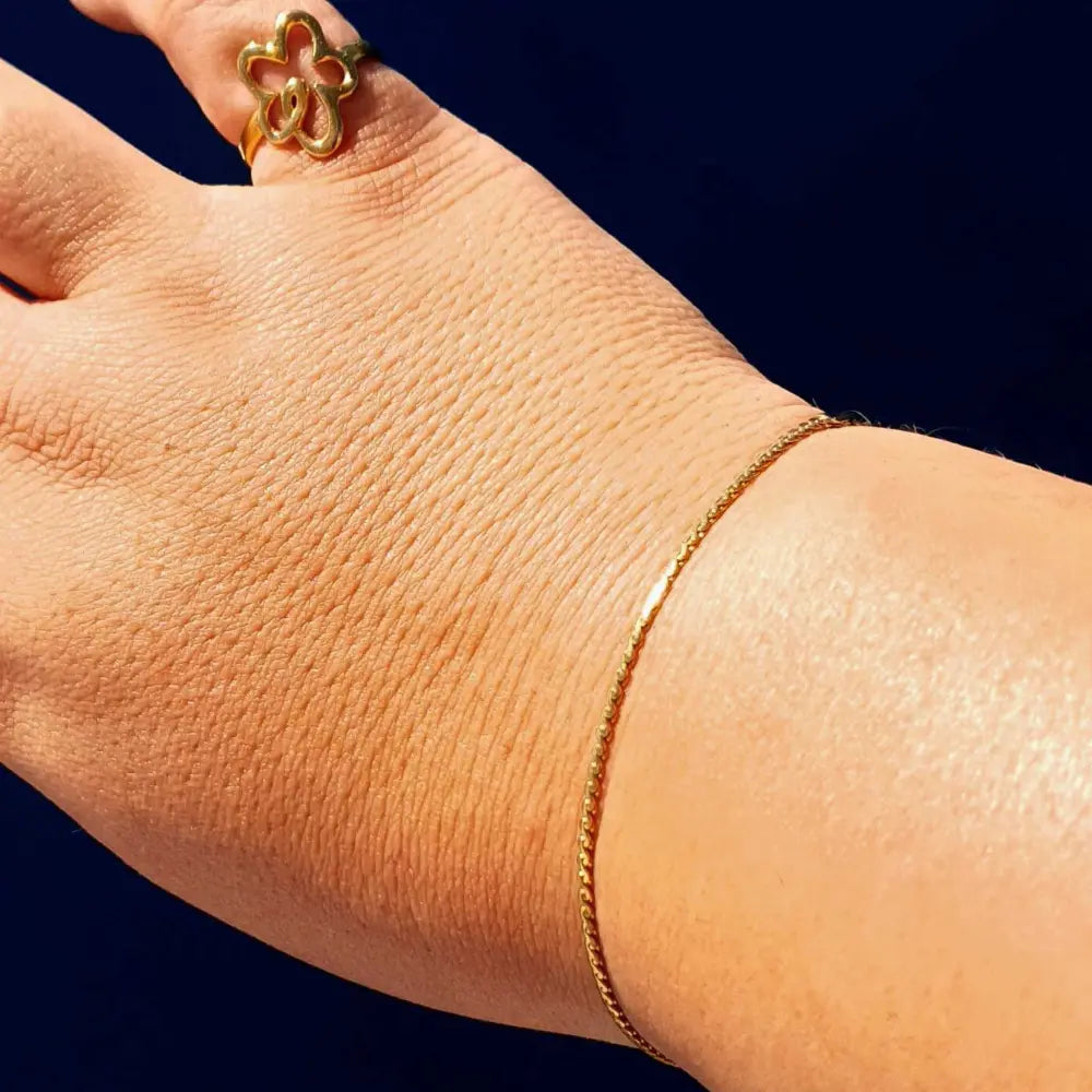 Plus-size woman’s hand wearing the Delicate Twist Chain Bracelet in 18k gold plating, featuring a fine twisted chain design for a subtle, elegant touch.