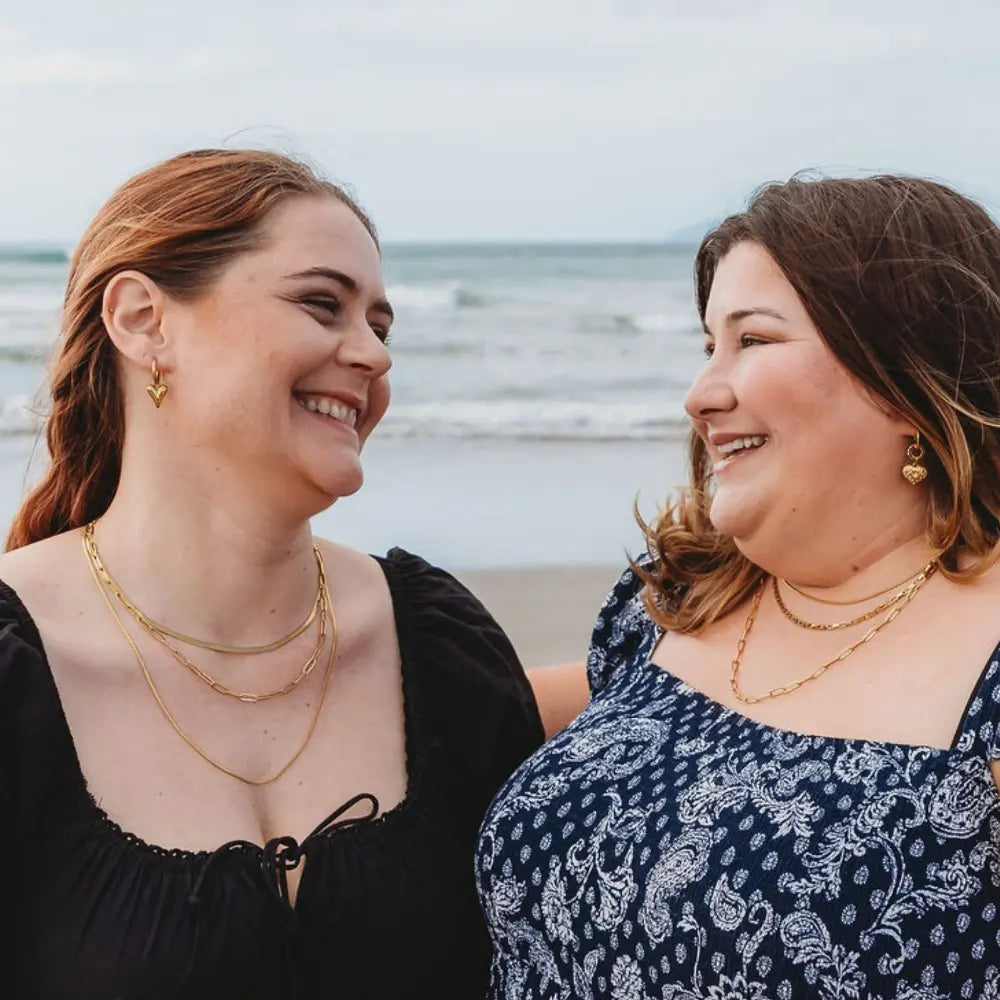 Two models, including a plus-size woman, showcasing the inclusive paperclip chain necklace, designed to fit every body beautifully.