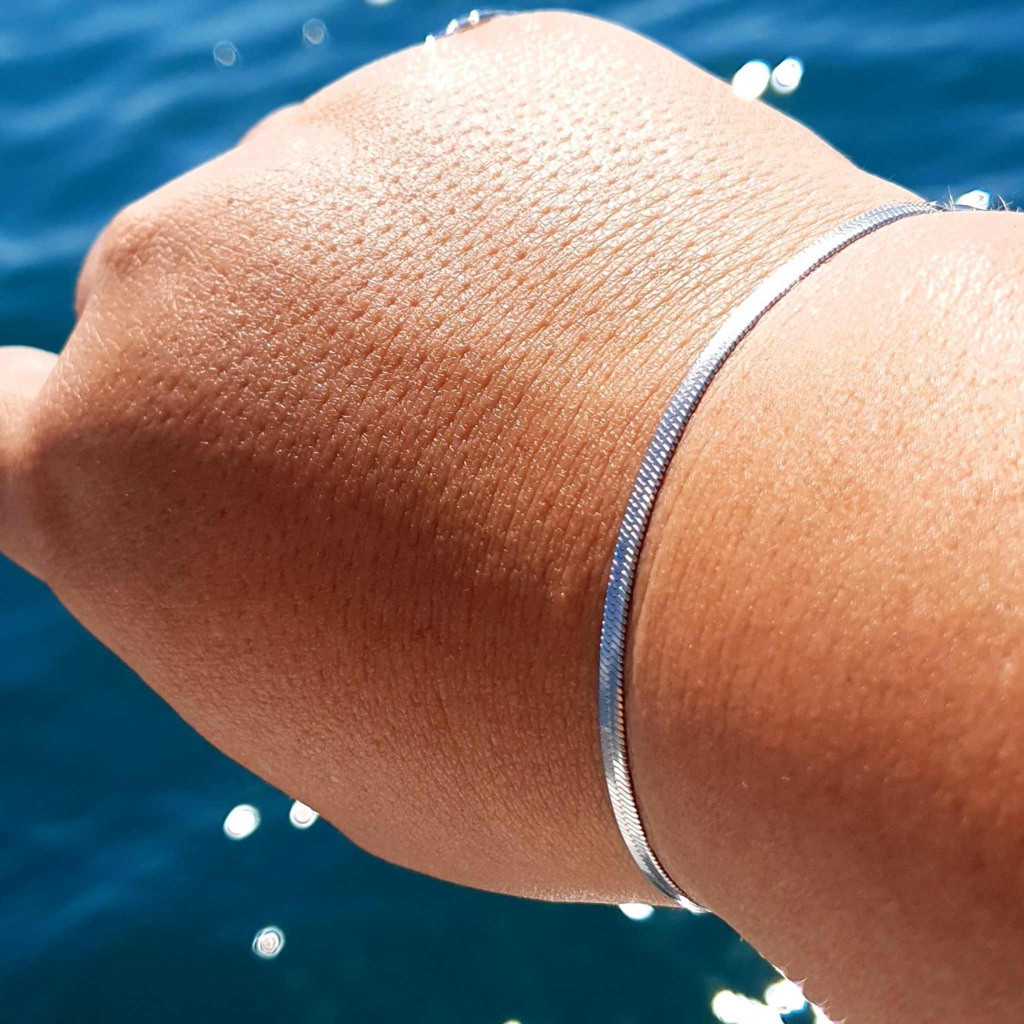 Woman wearing a sleek silversnake chain bracelet with adjustable fit, 15cm plus 5cm extender, also offered in gold-plated.