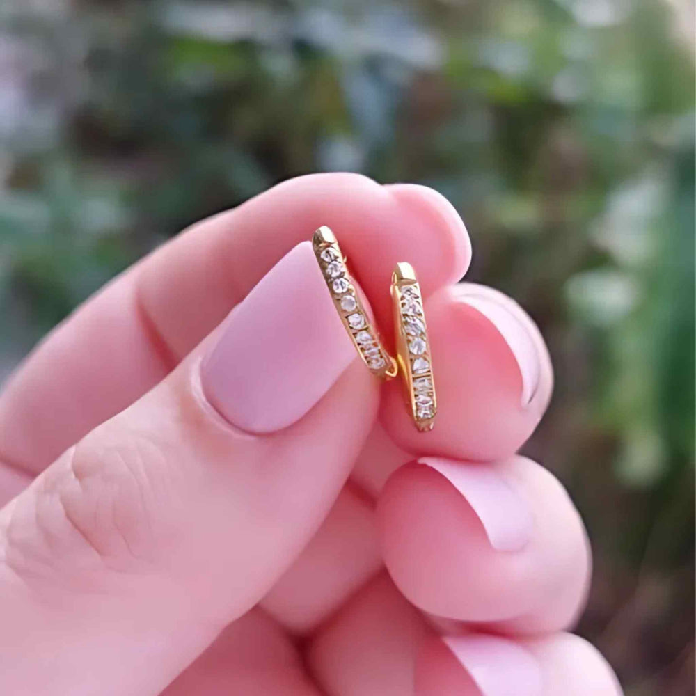 Woman holding gold-plated Embrace Huggies featuring delicate cubic zirconia detailing