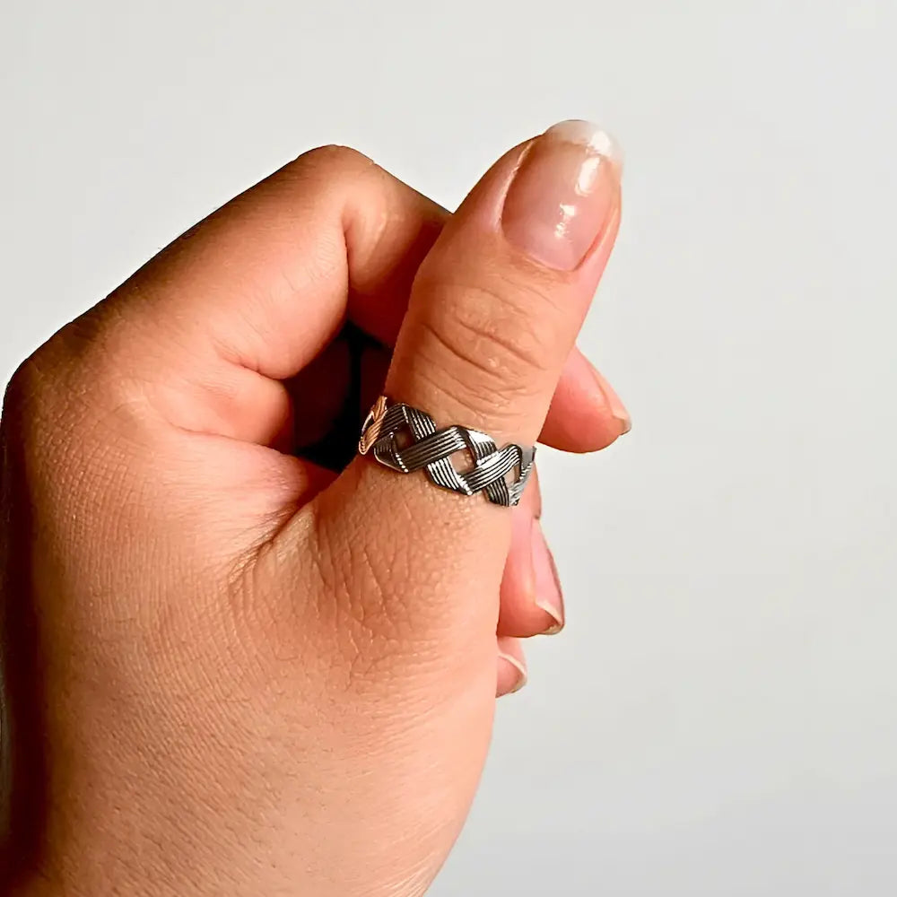 Woman wearing a silver crisscross adjustable ring with layered band style in stainless steel