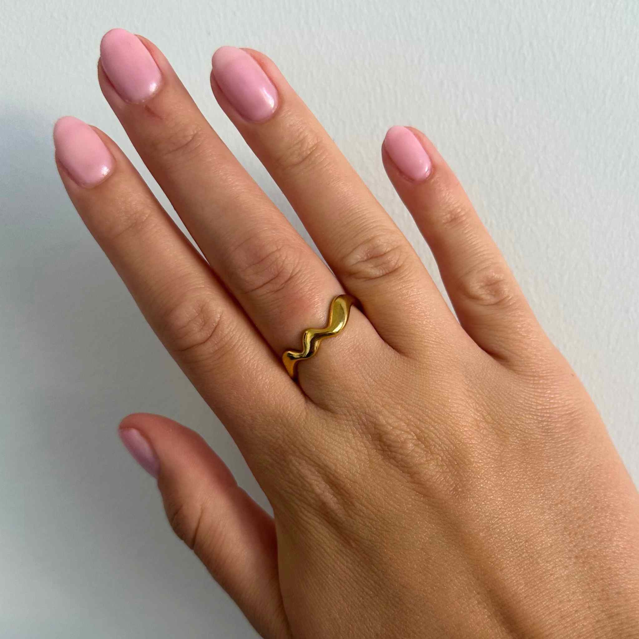 Woman wearing the Elegant Waves adjustable ring in gold-plated stainless steel with flowing, wave-inspired design