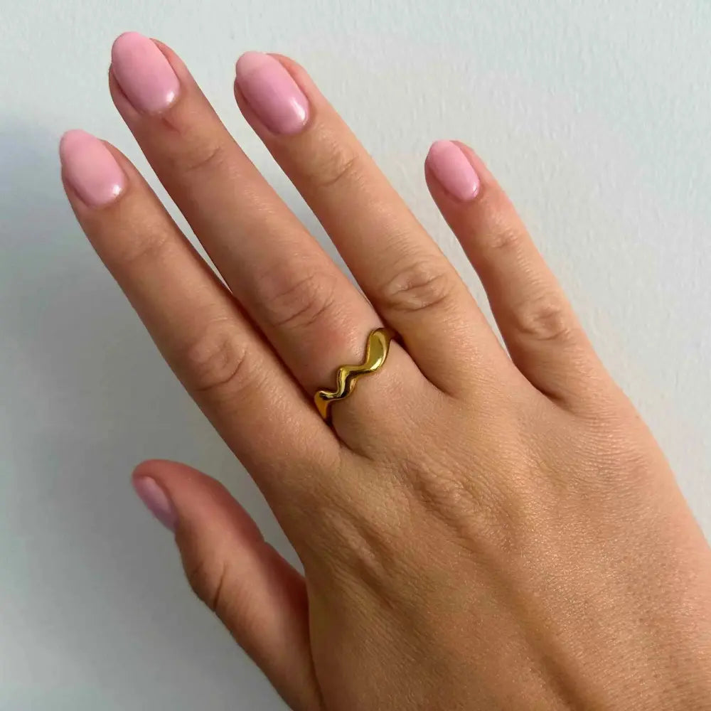 Woman wearing the Elegant Waves adjustable ring in gold-plated stainless steel with flowing, wave-inspired design