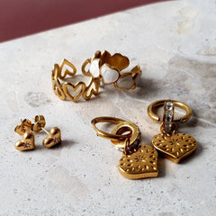 Flat lay of the Golden Love Bundle featuring 18K gold-plated Glimmer Hoops, Heartbeat Studs, My Forever Love Adjustable Ring, and Eternal Hearts Adjustable Ring – a matching gold earring and ring set that’s waterproof, hypoallergenic, and designed to fit all sizes.