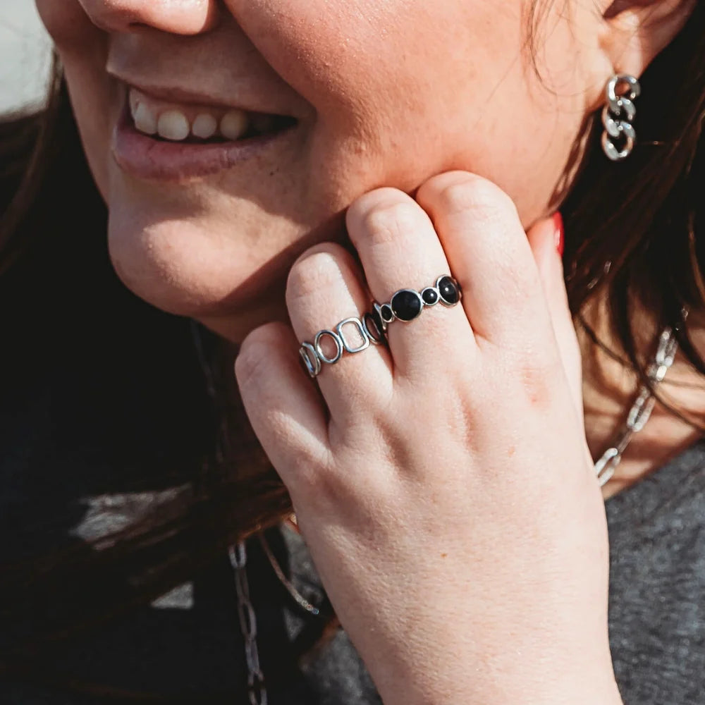 Woman wearing Harmonic Shapes and Bubbles adjustable rings in silver stainless steel, featuring sculptural curves and rounded bubble details