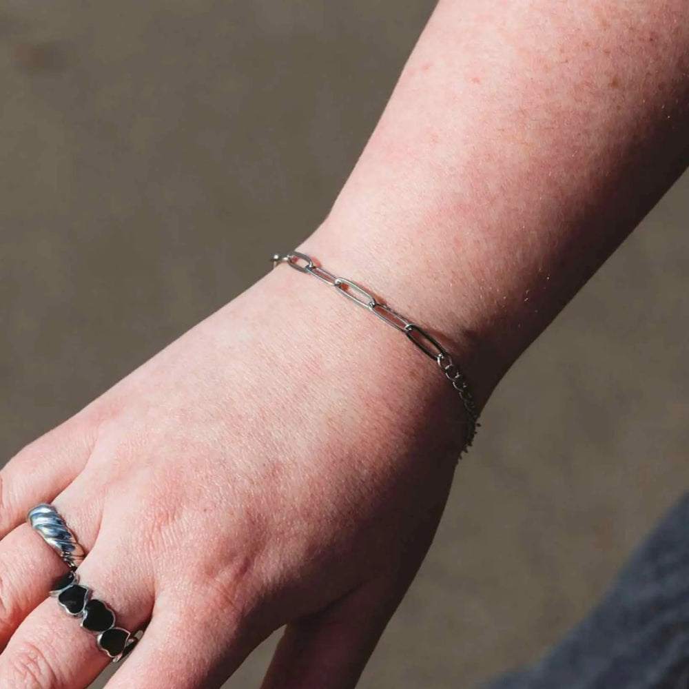 Woman wearing the Linked Up silver paperclip bracelet with elongated chain links in stainless steel for a modern, minimalist look