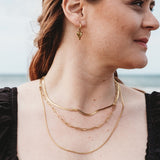 Model showcasing a stacked look with three gold-plated necklaces: Snake Chain, Paperclip Chain, and Delicate Twist Chain. Elegant and versatile, perfect for layering.