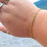 Woman wearing a minimalist gold-plated paperclip bracelet with elongated links, adjustable fit, also comes in silver