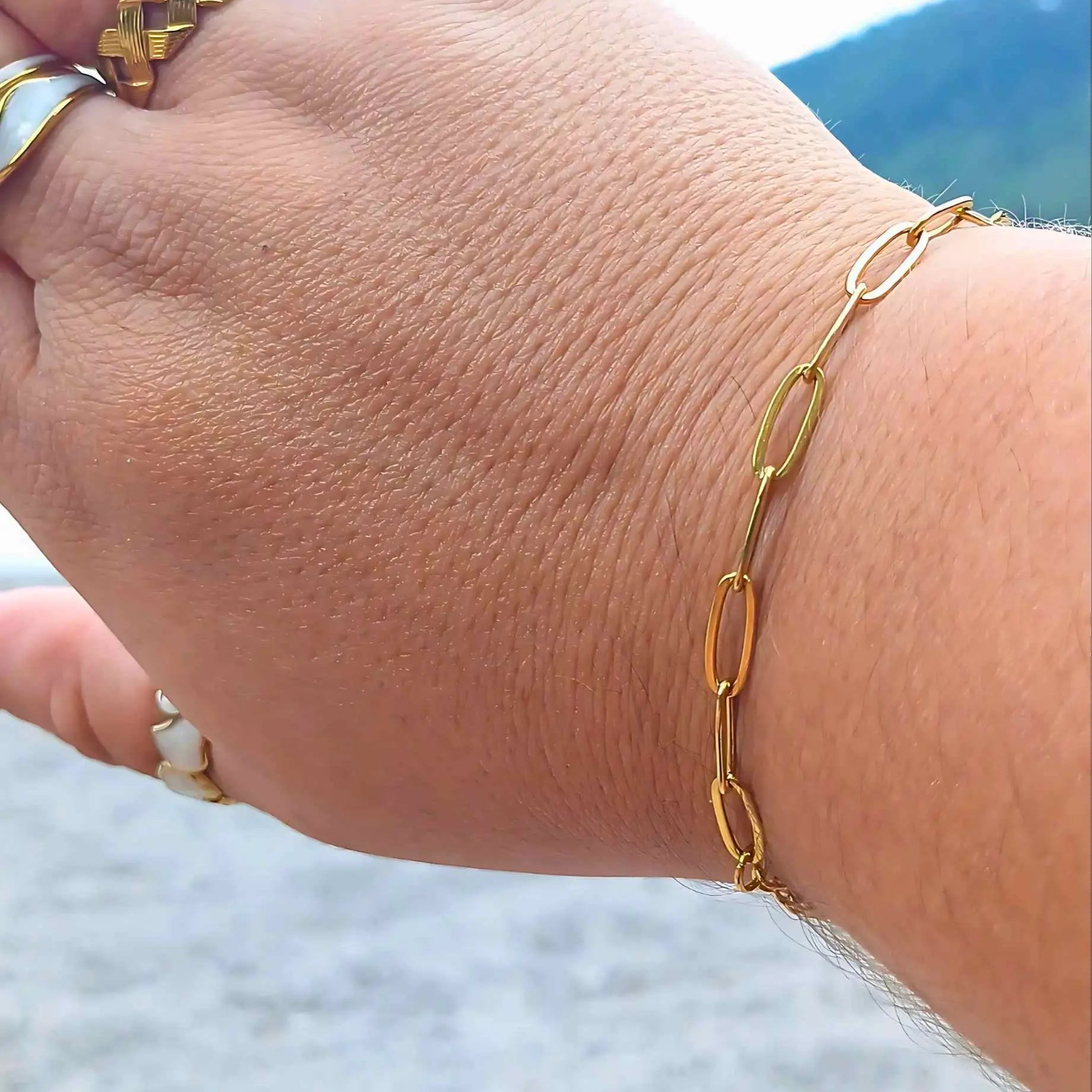 Woman wearing a minimalist gold-plated paperclip bracelet with elongated links, adjustable fit, also comes in silver