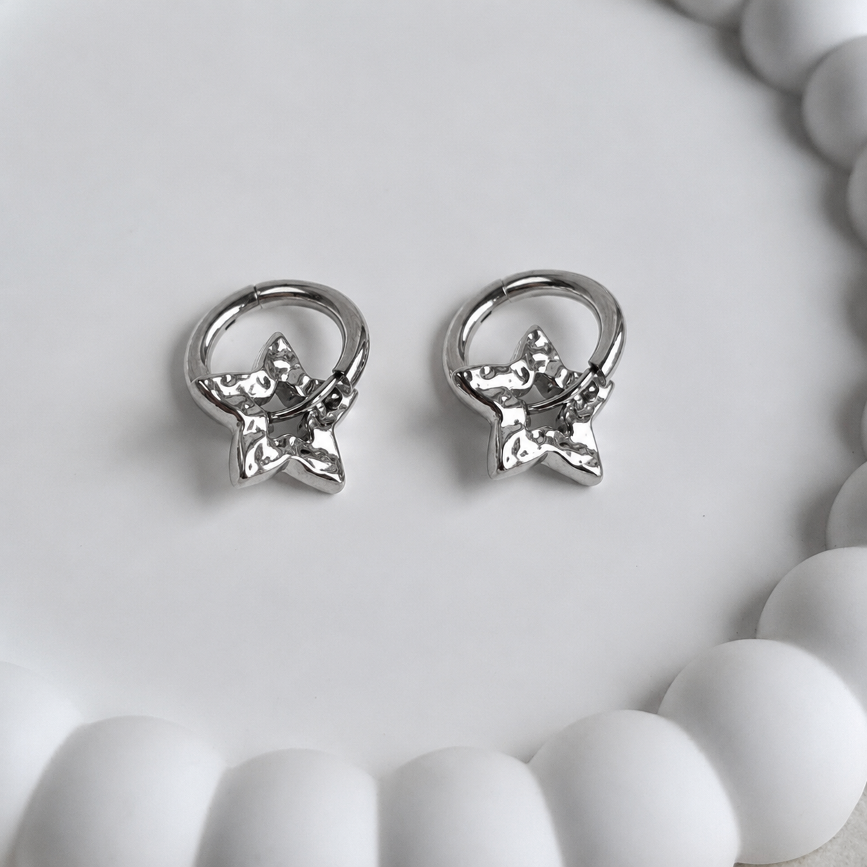 Pair of silver star-shaped earrings on a white surface