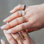 Ring stack with multiple gold rings on a plus sized womans hand. Stunning size-inclusive rings. 