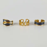 Three-piece gold ring bundle showcasing 18K gold-plated adjustable rings with striking black oil-dripping accents, waterproof, hypoallergenic, and made to fit every finger.